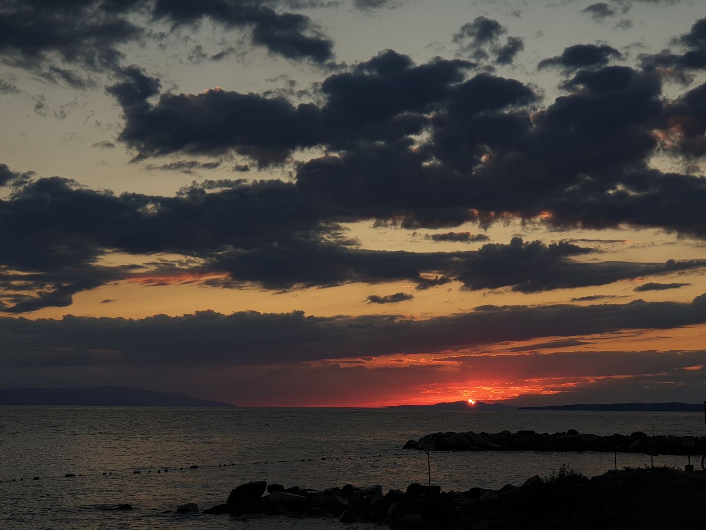 Ein goldener Sonnenuntergang über Wasser und fernen Hügeln